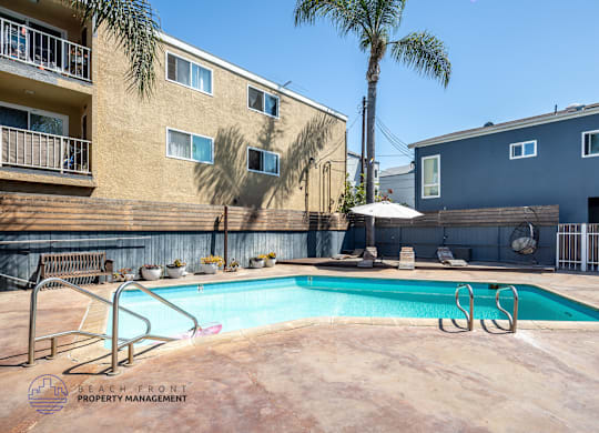 A pool surrounded by a metal fence and a building with a balcony.