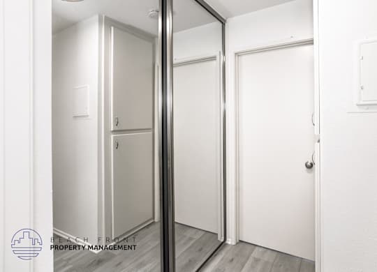A white door is in a room with a mirror on the wall.