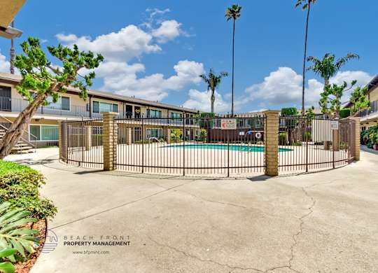 A pool surrounded by a fence with palm trees in the background.