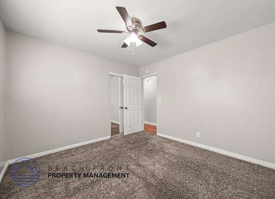 A room with a carpet floor and a ceiling fan.