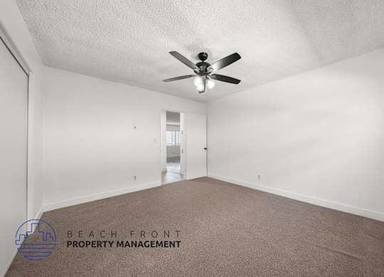 A room with a ceiling fan and carpeted floor.