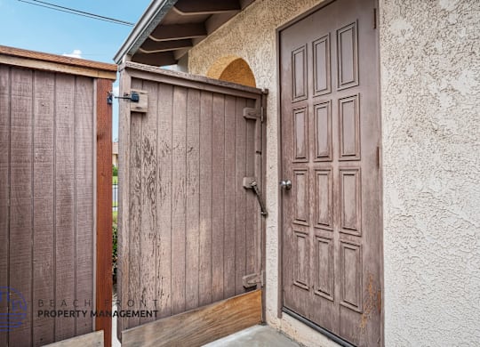 A wooden gate is closed with a brown door to the right.