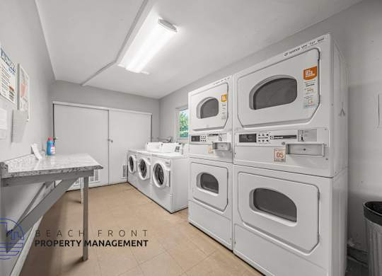 A laundry room with washers and dryers and a sign that says Beach Front Property Management.