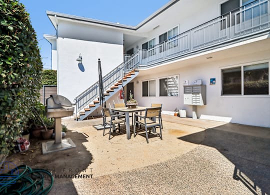 A white building with a balcony and a staircase leading to the second floor.