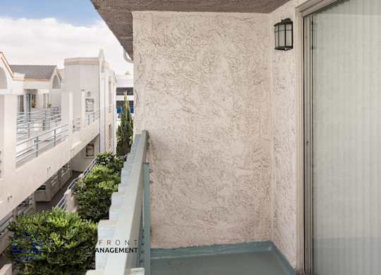 A balcony with a railing and a wall with a window.