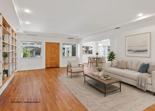 A living room with a white couch, wooden coffee table, and a painting on the wall.
