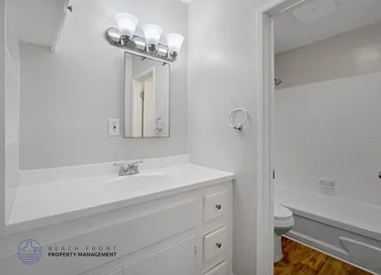 A white bathroom with a sink, mirror, and toilet.