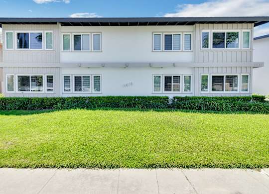 A white building with a green lawn in front.