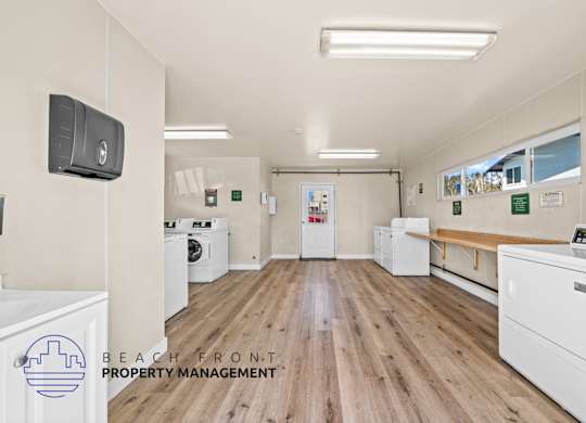 A laundry room with washers and dryers, a bench, and a sign for Beach Front Property Management.