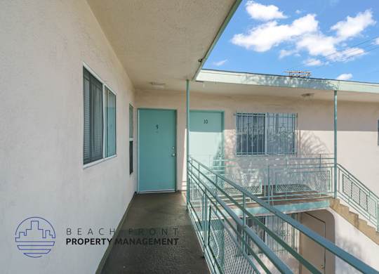A balcony with a glass railing and a blue door.