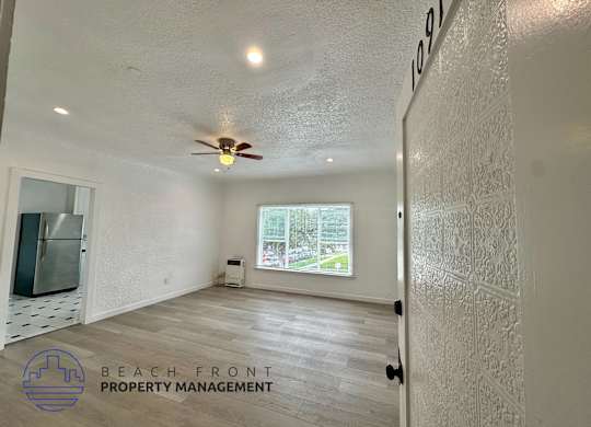 A room with a ceiling fan and a window overlooking a street.
