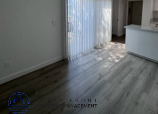 A room with wooden flooring and a window with curtains.