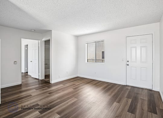 A room with wooden flooring and white walls.
