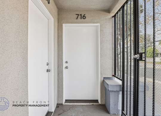 A white door with a black gate and a trash bin next to it.