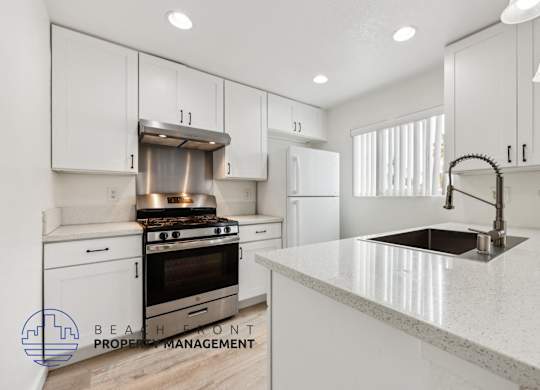 A modern kitchen with white cabinets and a stainless steel sink.