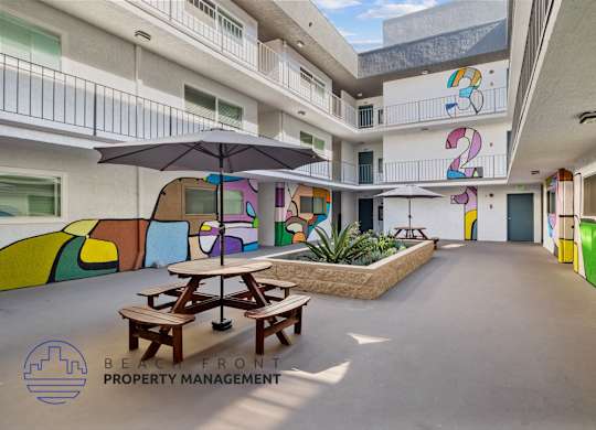 A colorful mural on the side of a building with a picnic table and umbrella in front.