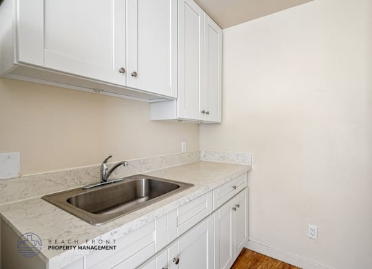 A kitchen with white cabinets and a marble countertop.