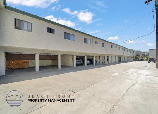 A parking lot in front of a building with the logo of Beach Front Property Management.