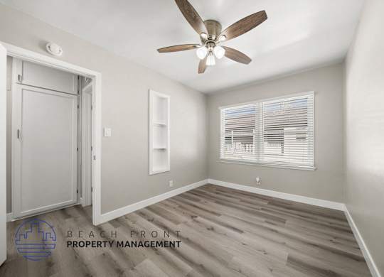 A room with a ceiling fan and a window with blinds.