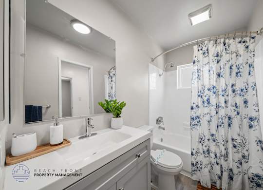 A bathroom with a white sink, toilet, and shower curtain.