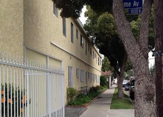 A street view of a residential area with a house and a tree.