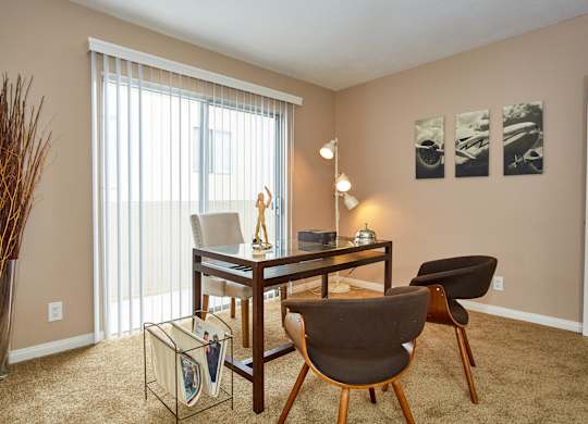 a desk and chairs in a living room with a large window