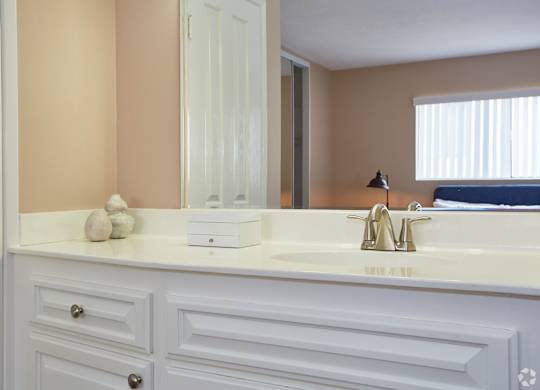 a bathroom with white cabinets and a large mirror