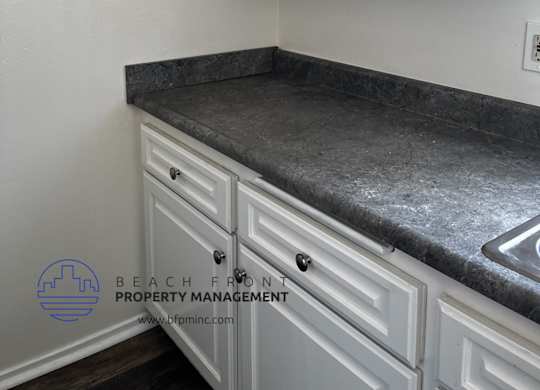 a kitchen with white cabinets and gray countertops