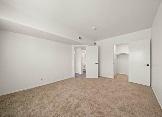 A large, empty room with carpeted flooring and white walls.