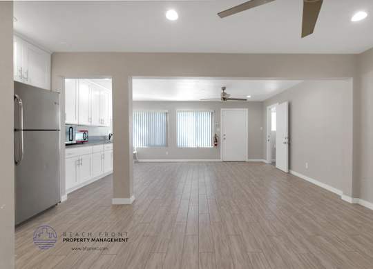 A spacious kitchen and living room with wooden flooring and a ceiling fan.