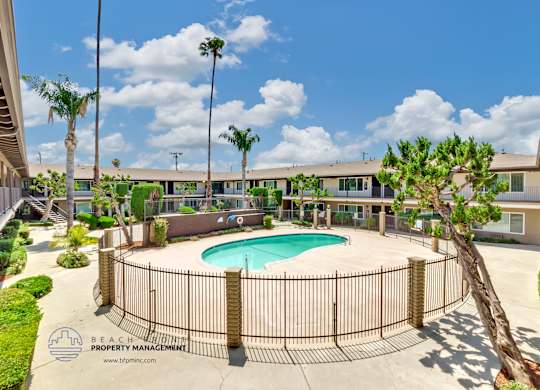 A pool surrounded by a fence with the words Beach Property Management on it.