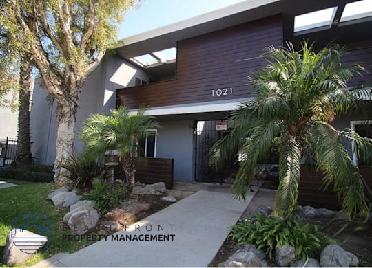 A building with the number 1021 on it is surrounded by plants and trees.