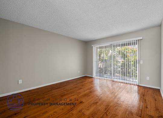A room with wooden floors and a window with blinds.