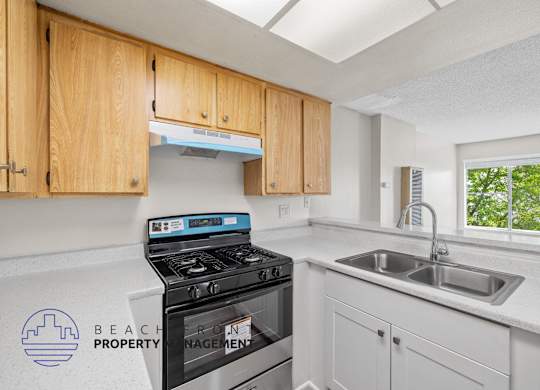 A kitchen with a stove, sink and cabinets.