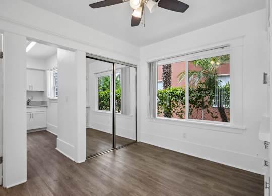 A room with a ceiling fan and sliding glass doors.