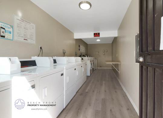 A laundry room with washers and dryers and a sign that says Beach Front Property Management.