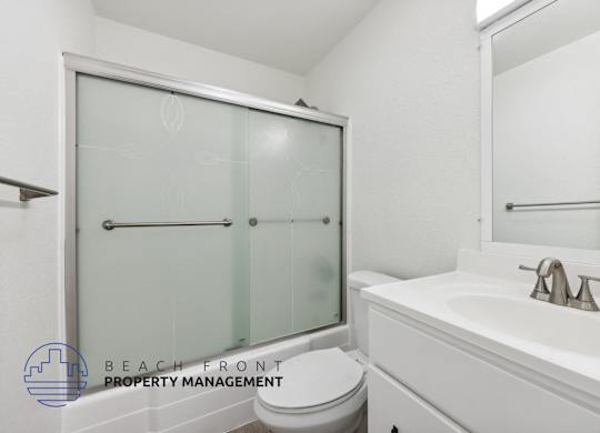 A white bathroom with a toilet, sink, and shower.