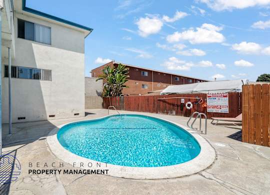 A pool surrounded by a concrete patio and a fence.