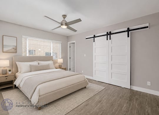 A bedroom with a bed, a ceiling fan, and a sliding door.