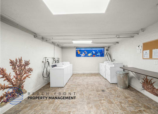view of onsite laundry room with  three washing and drying machines and a fish mural