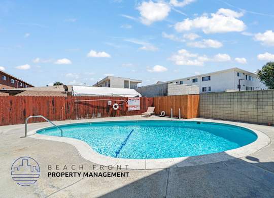 A pool surrounded by a fence with the words Beach Front Property Management on it.