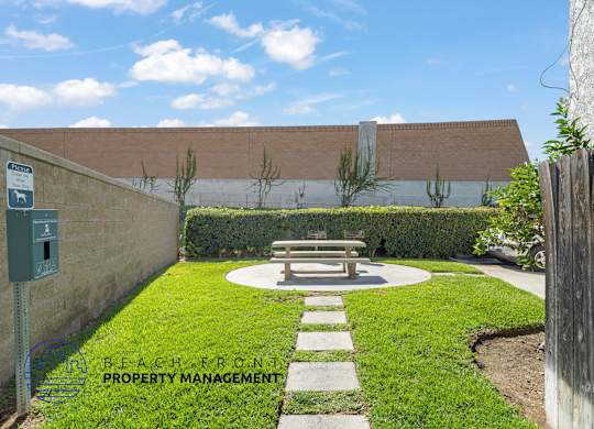 A park area with a bench and a sign for beach front property management.