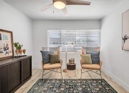 A room with two chairs and a table with a plant on it.