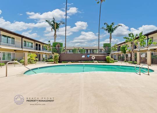 A pool surrounded by palm trees and apartment buildings.