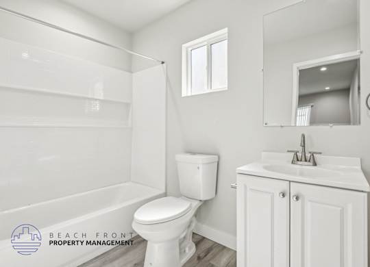 A white bathroom with a toilet, sink, and mirror.