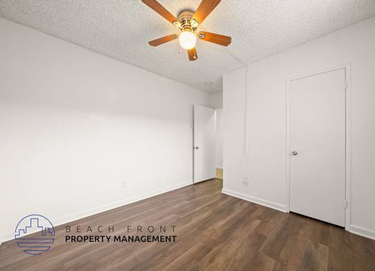 A room with a ceiling fan and wooden flooring.
