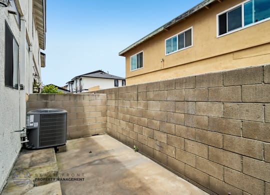 A concrete wall separates a patio from a house.
