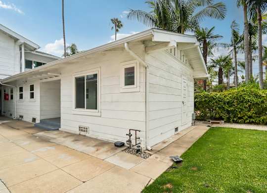 A small white house with a green lawn in front.