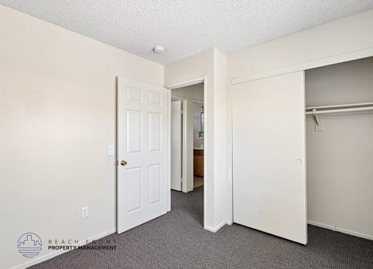 A room with a white door and a white closet with a shelf.