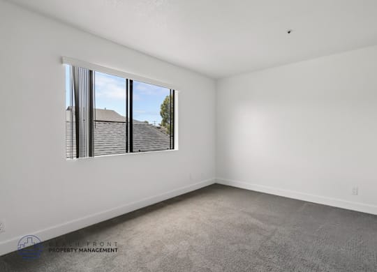 A room with a large window and a view of a house and trees outside.